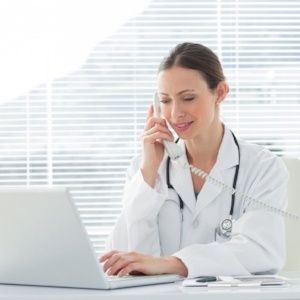 Beautiful female doctor talking on land line phone while using laptop at desk in clinic-248846-edited.jpeg